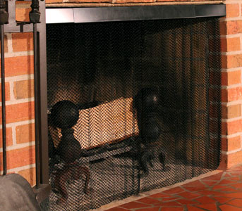 Satin black fireplace mesh screen and black rod and valance installed in brick fireplace