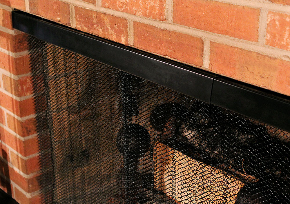 Black fireplace mesh screen and rod and valance kit shown at an angle